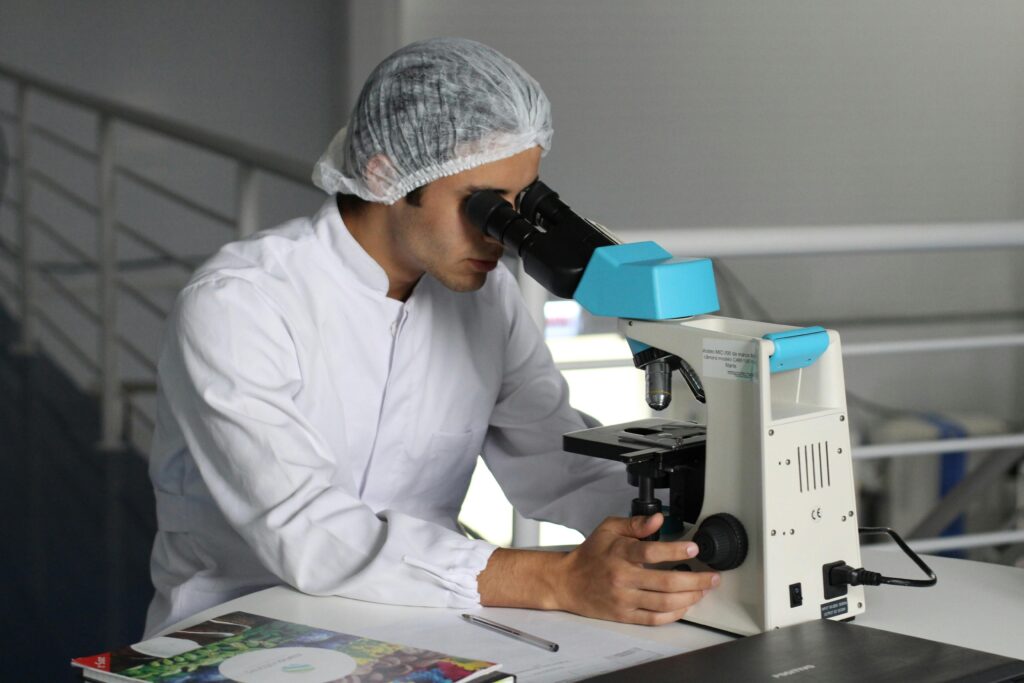 Mann im Labor untersucht Probe im Mikroskop