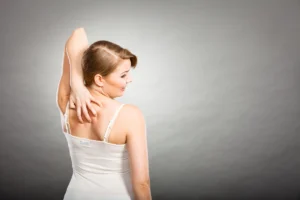 Frau mit Neurodermitis am Rücken kratzt sich